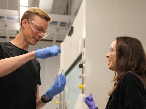 a male and female student in a lab wearing plastic gloves
