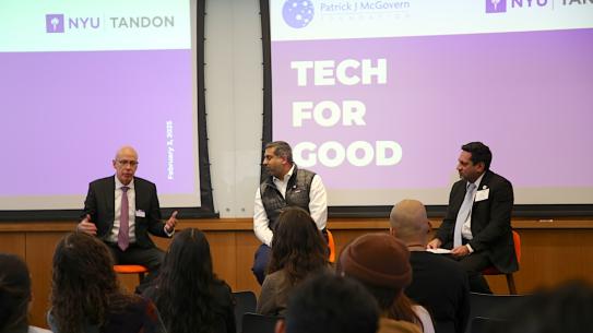 three men seated for a panel discussion in front of screen that says "Tech for Good"